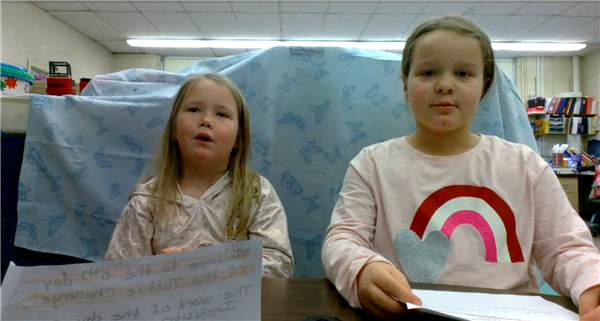  2 girls reading from paper 